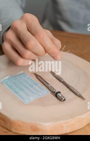 Trattamento di agopuntura sulle mani dell'uomo. Riabilitazione usando medicina alternativa. Strumenti di pressione su sfondo in legno. Foto Stock