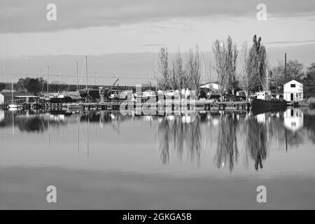 Immagine in bianco e nero. Riflessi autunnali a River.Beautiful paesaggio con alberi e barche al fiume Foto Stock