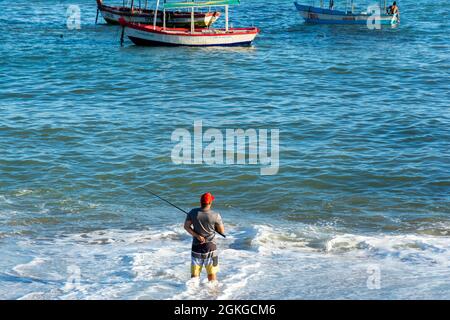 Salvador, Bahia, Brasile - 25 aprile 2021: Silhouette di pescatori con i loro pali al tramonto. Foto Stock