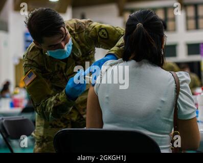 MANGILAO, Guam (16 aprile 2021) – PFC. Ethan Van Veldhuizen, uno specialista di medaglie di combattimento assegnato alla 25a Divisione di fanteria, somministra un vaccino COVID-19 a sostegno del team di vaccinazione COVID-19 del Dipartimento di Sanità pubblica e servizi sociali di Guam (DPHSS) presso una clinica di vaccinazione tenuta presso la Field House dell'Università di Guam Calvo. Il comando IndoPacifico degli Stati Uniti, attraverso l'Esercito Pacifico degli Stati Uniti, continua a fornire supporto flessibile al Dipartimento della Difesa dell'Agenzia federale per la gestione delle emergenze come parte della risposta dell'intero governo al COVID-19. Foto Stock