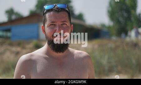 Un ritratto autentico di un giovane uomo fiducioso che guarda la fotocamera. Primo piano vista laterale di un giovane uomo naturale sulla spiaggia. Foto Stock