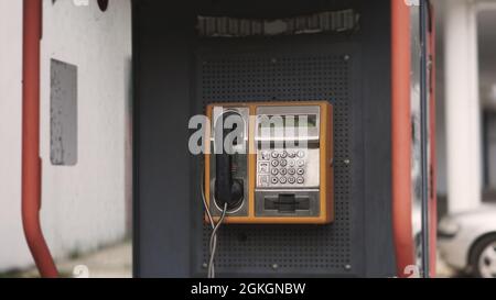 Cabina telefonica vecchia di linea fissa sulle strade della città. Telefono pubblico retrò. Concetto di vecchia tecnologia, telecomunicazioni del passato e vintage Foto Stock