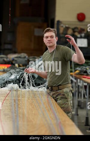 SGT. Ryan Clifford, un paracadute rigger con il 403esimo Quartermaster Rigger Support Team della Guardia Nazionale del North Carolina, separa i cavi mentre impacchettano un paracadute a Fort Bragg, North Carolina, 17 aprile 2021. Monje si ferma diverse volte durante tutto il processo e ha una seconda persona ispezionare il suo lavoro come parte delle misure di controllo di qualità in atto per imballaggio paracadute. Foto Stock