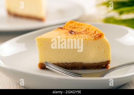 Pezzo di deliziosa cheesecake fatta in casa servita su un piatto bianco Foto Stock