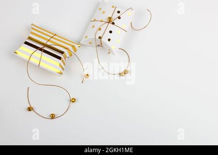 Due confezioni regalo con campane dorate e stelle su sfondo bianco. Buon Natale e Capodanno concetto. Biglietto di auguri. Spazio di copia. Disposizione piatta. Foto Stock