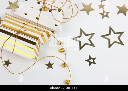 Due confezioni regalo con campane dorate e stelle su sfondo bianco. Buon Natale e Capodanno concetto. Biglietto di auguri. Spazio di copia. Disposizione piatta. Foto Stock