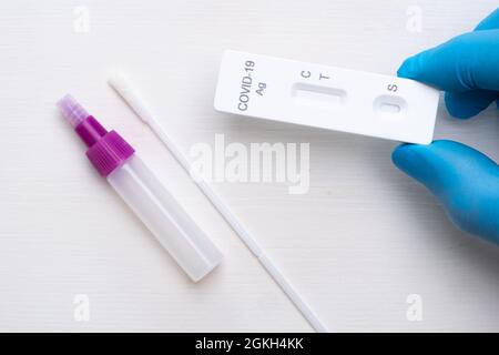 Nuovo test antigenico per coronavirus e kit per diagnostica rapida in mano medica con guanti di gomma su sfondo bianco Foto Stock