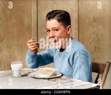 1940 ANNI '30 SORRIDENDO RAGAZZO AFFAMATO GUARDANDO MACCHINA FOTOGRAFICA MANGIARE LA CIOTOLA DI CEREALI CON UN CUCCHIAIO E UN BICCHIERE PIENO DI LATTE - F8185C HAR001 HARS HEALTHINESS CASEIFICIO COPIA SPAZIO HALF-LENGTH MASCHI ESPRESSIONI OCCHIO CONTATTO PREMEEN RAGAZZO AFFAMATO FELICITÀ ALLEGRO DI SORRISI GIOIOSI GIOVANI PRE-TEEN RAGAZZO PRE-TEEN ETNIA CAUCASICA HAR001 VECCHIO STILE Foto Stock