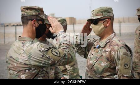 Il Coll. Brian Kibitlewski, comandante, Battaglione delle truppe speciali, 1° comando di sostegno al Teatro, SPC. Carlos Vasquez, 1° TSC, si scambiano saluti durante una cerimonia di premiazione a Camp Arifjan, Kuwait, 22 aprile 2021. Vasquez è stata insignita della Medaglia Army Achievement per essere parte integrante della creazione del posto di comando di spedizione che dà al TSC la capacità di avere una capacità operativa in avanti per fornire supporto di livello operativo in tutto il mondo. Foto Stock