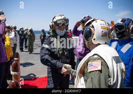 Nicholas Hué, capo dell'unità di gestione, missione e supporto aeromobili, l'Agenzia francese per gli acquisti di armamenti (DGA) saluta il Capitano Paul J. Lanzilotta, USS Gerald R. Ford (CVN 78) comandante ufficiale quando arriva a bordo di Ford per una visita alla nave, 23 aprile 2021. La dirigenza DGA ha visitato Ford per vedere il sistema di lancio degli aeromobili elettromagnetici (EMALS) e l'avanzato dispositivo di arresto (AAG) in funzione, per consentire alla Francia di perfezionare il design del futuro vettore francese. La Francia procurerà EMALS e AAG e l'adozione di un modello di operazioni di volo su ponte di classe Ford Foto Stock