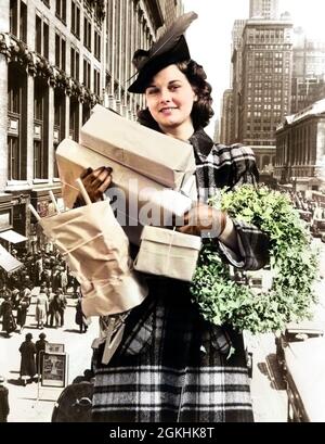 DONNA DEGLI ANNI '30 ANNI '40 CHE GUARDA LE BRACCIA DELLA FOTOCAMERA PIENO DI PACCHETTI SHOPPING NATALIZI E WREATH COMPOSITO CON STREET SCENE - X318C HAR001 HARS SALUBRITÀ COPIA SPAZIO MEZZA LUNGHEZZA PERSONE CRESCIUTE PACCHETTO ESPRESSIONI INVERNO SHOPPER OCCHIO CONTATTO INVERNO STAGIONE FELICITÀ CENTRO URBANO COMPOSITO ECCITAMENTO HOLLY NYC DICEMBRE CARTA MARRONE NEW YORK ELEGANTI PACCHETTI STAGIONE GIOVANE ADULTO DONNA 42ND STREET ETNIA CAUCASICA COMPOSIZIONE HAR001 VECCHIO STILE Foto Stock