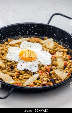 lenticchie con carne affumicata e cipolla servite con uova fritte Foto Stock