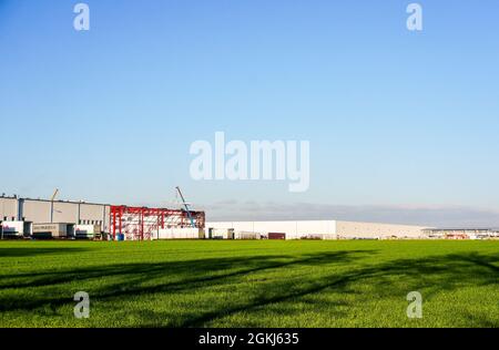 GADKI, POLONIA - 18 ottobre 2016: Il campo agricolo verde e un edificio industriale in lontananza a Gadki, Polonia Foto Stock