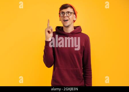 bel giovane uomo ha avuto un'idea, un ragazzo in un cappello arancione e un maglione rosso ha trovato una via d'uscita dalla situazione, una soluzione al problema Foto Stock