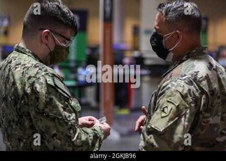 U.S. Navy Petty Officer terza classe Bake Sylvester, a sinistra, assegnato al Naval Medical Center Portsmouth, Virginia, riceve una moneta da U.S. Army Briga. Gen. Ronald Cuples, a destra, l'assistente generale della Guardia Nazionale del Massachusetts, presso il Centro di vaccinazione della Comunità presso l'Hynes Convention Center di Boston, 30 aprile 2021. I membri del servizio degli Stati Uniti provenienti da tutto il paese sono schierati a sostegno delle operazioni federali di risposta al vaccino del Dipartimento della Difesa. Il comando del Nord degli Stati Uniti, attraverso il Nord dell'esercito degli Stati Uniti, rimane impegnato a fornire il continuo e flessibile servizio del Dipartimento della Difesa Foto Stock