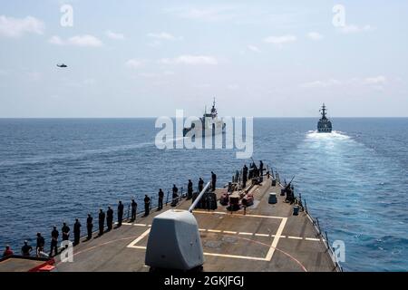 MAR ARABICO (2 maggio 2021) – cacciatorpediniere missilistico guidato USS Laboon (DDG 58) opera in formazione con la fregata della Marina pakistana PNS Saif (F 253), a destra, la fregata della Marina canadese reale HMCS Calgary (FFH 335) E un elicottero Royal Canadian Air Force CH-148 Cyclone durante un esercizio di passaggio nel Mar Arabico, 2 maggio. Laboon opera a sostegno diretto delle forze marittime combinate (CMF), un partenariato marittimo multinazionale che esiste per contrastare gli attori non statali illeciti in alto mare, promuovendo la sicurezza, la stabilità e la prosperità nel Golfo Persico, nel Mar Rosso, nel Golfo di Aden, nell'Oceano Indiano, Foto Stock