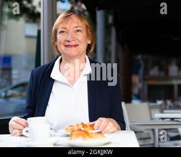 Donna anziana che fa colazione in caffetteria Foto Stock