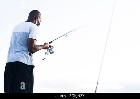 Salvador, Bahia, Brasile - 23 maggio 2021: Silhouette di pescatori con i loro pali al tramonto. Foto Stock