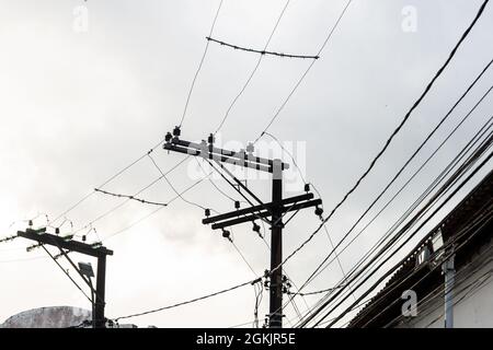 Vista di un polo di alimentazione elettrica con molti fili aggrovigliati. Strade di Salvador, Bahia, Brasile. Foto Stock