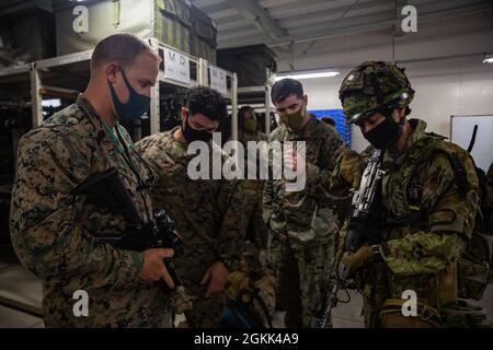 Un soldato giapponese con 1° reggimento di dispiegamento rapido anfibio, Japan Self Defense Force, indica le diverse parti di un sistema di impegno laser integrato multiplo (MIGLIA) a Camp Ainoura, Sasebo, Giappone, 12 maggio 2021, Durante l’esercizio Jeanne D’ Arc 21. LA tecnologia MILES consente alle truppe di condurre una forza realistica sull'addestramento di combattimento della forza. ARC-21 è un'opportunità per le forze statunitensi, francesi, giapponesi e australiane di condividere esperienze, tattiche e Best practice per affinare insieme le proprie competenze. Foto Stock