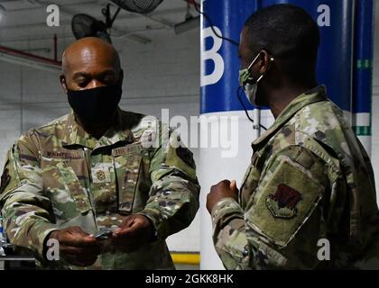 Consigliere senior arruolato al Capo, il National Guard Bureau Tony Whitehead guarda una moneta presentata a lui da Tech. SGT. Moses Ssemugenyi, un membro della 102a ala di intelligenza della Guardia Nazionale aerea del Massachusetts, durante una visita per incontrare i membri della Guardia Nazionale assegnati alla missione Capitol Response a Washington, D.C., 14 maggio 2021. La Guardia Nazionale è stata invitata a continuare a sostenere le forze dell'ordine federali con sicurezza, comunicazioni, evacuazione medica, logistica e supporto alla sicurezza per le agenzie statali, distrettuali e federali fino alla metà di maggio. Foto Stock