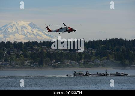 Un settore Columbia River MH-60 Jayhawk elicottero equipaggio vola sopra Maritime Security Response Team West equipaggio barca il 13 maggio vicino Fox Island, WA, in vista di Mt. Rainier. Più risorse e personale di unità hanno partecipato a un esercizio di sicurezza marittima per mostrare le competenze e l'interoperabilità degli equipaggi della Guardia Costiera in caso di minaccia di emergenza. Foto Stock