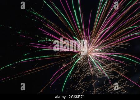 fuochi d'artificio orizzontali verdi e rosa in cielo di notte Foto Stock