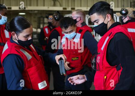 210515-N-NM271-2010 OCEANO PACIFICO (15 maggio 2021) – Aviation Ordnanceman 3rd Class Marisol Sanchez, a sinistra, da Miami, distribuisce munizioni ai marinai durante un tiro a pistola a bordo della nave d'assalto anfibio USS Tripoli (LHA 7), maggio 15. Tripoli sta conducendo operazioni di routine nella terza flotta statunitense. Foto Stock