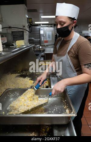 OCEANO PACIFICO (15 maggio 2021) Specialista culinario Seaman Noelle Searfoss, di Towanda, Penn., prepara il cibo a bordo della nave d'assalto anfibio USS Essex (LHD 2), maggio 16. Marinai e marines dell'Essex Amphibious Ready Group (ARG) e dell'XI Marine Expeditionary Unit (MEU) sono in corso al largo delle coste della California meridionale. Foto Stock