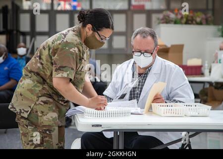 Kirsten Allen del Maryland state Medical distaccamento, e il Dr. Tony Gearhart, un farmacista di Safeway con sede ad Hannover, Maryland, passa attraverso la documentazione all'evento di vaccinazione DEI CHIMES all'Aeroporto Internazionale Thurgood Marshall di Baltimora/Washington il 17 maggio 2021. Safeway, una società di supermercati, e la Vaccine Equity Task Force del Maryland, hanno collaborato per vaccinare i membri DEI CHIMES, un’organizzazione senza scopo di lucro che assiste le persone con sfide intellettuali e comportamentali per raggiungere il loro massimo potenziale, al fine di garantire l’equità dei vaccini in tutto il Maryland. Foto Stock