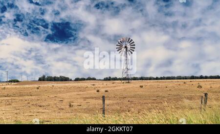 Un mulino a vento in piedi in un paddock di vasti spazi aperti nel paese dell'entroterra australiano Foto Stock