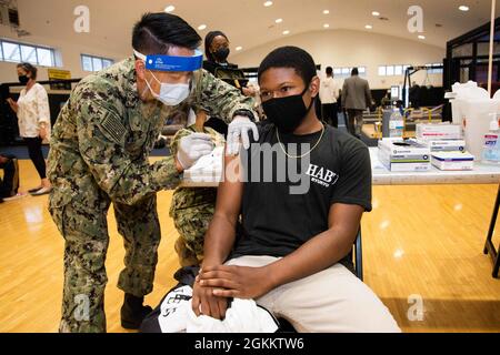 YOKOSUKA, Giappone (20 maggio 2021) – Jaylen Prince, uno studente della Kinnick High School di 17 anni, riceve il vaccino Pfizer COVID-19 dal Lt. Erich Chen, assegnato all'Ospedale Navale degli Stati Uniti Yokosuka, durante una distribuzione del vaccino presso il Nido Hawk del comandante, Fleet Activities Yokosuka (CFAY). Con l'autorizzazione del Dipartimento della Difesa, la CFAY ha iniziato a somministrare vaccini a bambini da 12 a 17 anni con contratto di status of Forces Agreement sponsorizzato dalla Marina durante i due giorni di distribuzione. Per più di 75 anni, CFAY ha fornito, mantenuto e gestito le strutture e i servizi di base a sostegno della settima fuga degli Stati Uniti Foto Stock