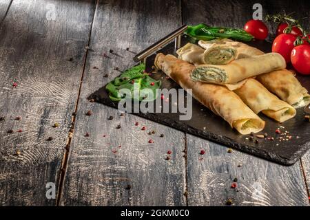 Pancake con formaggio e spinaci su sfondo di legno scuro Foto Stock