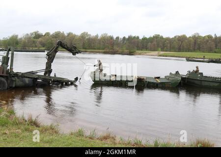 I soldati della riserva dell'esercito dalla 652a compagnia di ingegneri si preparano ad agganciare una parte del ponte a nastro migliorato per rimuoverlo dall'acqua e trasportarlo in un'altra posizione come parte dell'addestramento a Fort McCoy, Wis., 21 maggio 2021. L'addestramento permette a questo Hammond, Wis., basato l'unità di costruzione del ponte per diventare più competente nella costruzione dei punti di attraversamento per i convogli militari di veicoli gommati o cingolati. Foto Stock