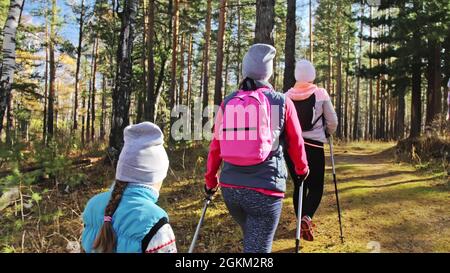 La donna fa nordic walking in natura. Ragazze e bambini usano bastoni da trekking e bastoni nordici, zaini. La famiglia viaggia e va in per lo sport. Autunno Foto Stock