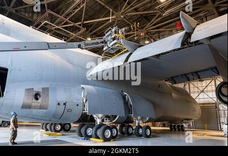 Senior Airman Tyler Bryce, a sinistra, spot staff Sgt. Brandin Josey, centro, e Airman 1st Class Brandon Camp, tutti 60th manutenzione Squadron specialisti di riparazione aerospaziale, come essi utilizzano un sollevatore telescopico durante un C-5M Super Galaxy pannello di ispezione a battente 21 maggio 2021, Travis Air Force base, California. Il C-5 è il più grande velivolo dell'inventario delle forze aeree e la sua missione principale è quella di trasportare carichi e personale per il Dipartimento della Difesa. Foto Stock