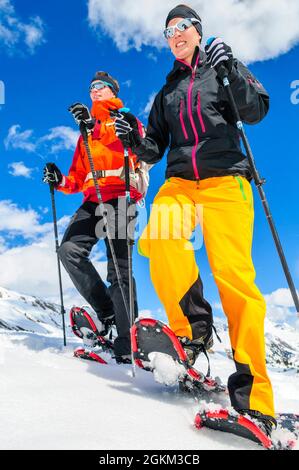 Coppia giovane escursionismo con le racchette da neve in una bella giornata nel tardo inverno Foto Stock