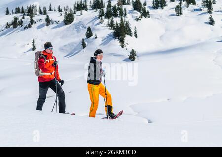 Coppia giovane escursionismo con le racchette da neve in una bella giornata nel tardo inverno Foto Stock