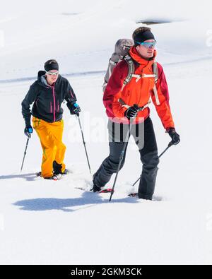 Coppia giovane escursionismo con le racchette da neve in una bella giornata nel tardo inverno Foto Stock
