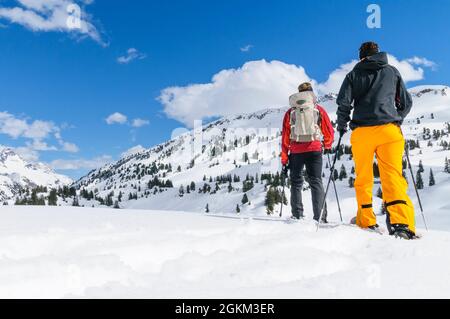Coppia giovane escursionismo con le racchette da neve in una bella giornata nel tardo inverno Foto Stock