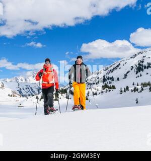 Coppia giovane escursionismo con le racchette da neve in una bella giornata nel tardo inverno Foto Stock