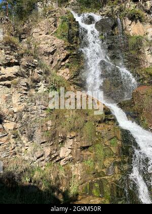 Primo piano di una potente cascata di alta qualità. Vista laterale di una cascata soleggiato nella natura selvaggia. Un grande flusso d'acqua si riversa verso il basso dal monte Foto Stock