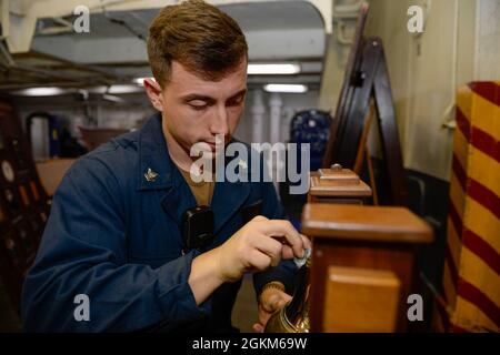 210523-N-WG572-1005 OCEANO PACIFICO (23 maggio 2021) – U.S. Navy Boatswains Mate 2nd Class Aron Harrelson, di Whiteville, N.C., brilla la campana del quarto piano a bordo della portaerei USS Theodore Roosevelt (CVN 71), 23 maggio 2021. Il gruppo Theodore Roosevelt Carrier Strike è in fase di implementazione programmata che conduce operazioni di routine nella terza flotta statunitense. Foto Stock