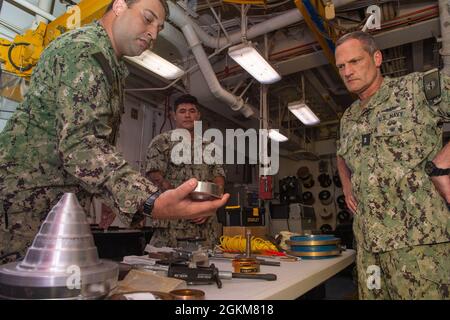 210524-N-SS370-1004 POLARIS POINT, Guam (24 maggio 2021) il Mate 2° Classe Mark Weinreich presenta le capacità del reparto di riavvolgimento del motore per l'ADM posteriore. Jeff Jablon, comandante, Submarine Force, U.S. Pacific Fleet, durante una visita programmata a bordo del sottomarino USS Frank Cable (AS 40), maggio 24. Jablon ha visitato il cavo e altre unità alla base navale Guam, per incontrare i marinai, discutere le operazioni delle unità con la leadership, e valutare le capacità delle aree di prima mano. Foto Stock