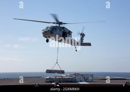 OCEANO PACIFICO (24 maggio 2021) un elicottero MH-60 Sea Hawk assegnato agli 'Indians' di Helicopter Sea Combat Squadron (HSC) 6 consegna munizioni al ponte di volo della portaerei USS Abraham Lincoln (CVN 72) durante un carico di munizioni. Abraham Lincoln sta conducendo un carico di munizioni nell'area di operazioni della terza flotta degli Stati Uniti. Foto Stock