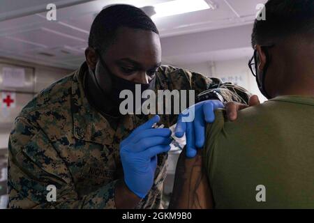 PACIFIC OCEAN (24 maggio 2021) Hospital Corpsman III Classe Malik Nicholson, di Brooklyn, N.Y., somministra un vaccino a bordo di nave d'assalto anfibio USS Essex (LHD 2), maggio 24. Marinai e marines dell'Essex Amphibious Ready Group (ARG) e dell'XI Marine Expeditionary Unit (MEU) sono in corso di formazione integrata al largo delle coste della California meridionale. Foto Stock