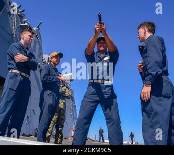 210524-N-MT581-1105 OCEANO PACIFICO (maggio. 24, 2021) U.S. Naval Academy Midshipman 2a classe Nick Straw, dal Libano, Ohio, centro, riceve l'addestramento di familiarizzazione delle armi da marinai a bordo di un molo di trasporto anfibio USS John P. Murtha (LPD 26), maggio 24. John P. Murtha sta conducendo operazioni di routine nella terza flotta degli Stati Uniti. Foto Stock