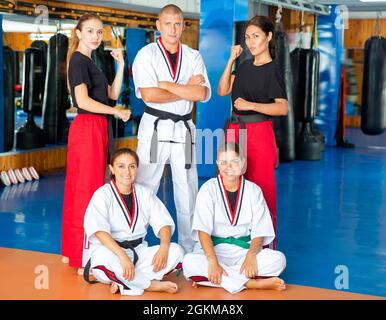 Donne sicure in kimonos con allenatore di arti marziali in palestra Foto Stock