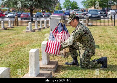 Un marinaio disposto presso il Naval Support Activity Hampton Roads Portsmouth stila bandiere sulle tombe dei membri del servizio caduti durante la cerimonia annuale di disposizione della bandiera al cimitero navale del memoriale di Captain Ted Conaway nel Naval Medical Center Portsmouth (NMCP) maggio 27. Foto Stock