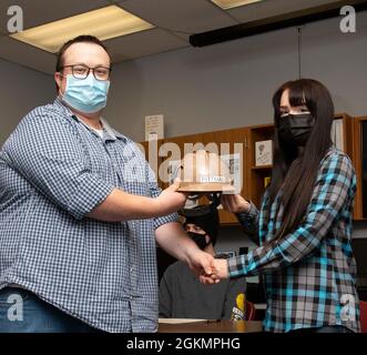 PORT ORCHARD, Washington (28 maggio 2021) – Ryan Reinke, General Foreman, Marine Machinist Shop, Trident Refem Facility Bangor (TRFB), presenta Alexandra Pittman, Senior, South Kitsap High School (SKHS), con un elmetto a SKHS maggio 28. Il personale di leadership di TRFB ha lavorato con i consulenti di SKHS per identificare tre anziani altamente motivati della scuola superiore che hanno un interesse nel lavoro commerciale e li ha intervistati per un potenziale impiego a TRFB. Foto Stock